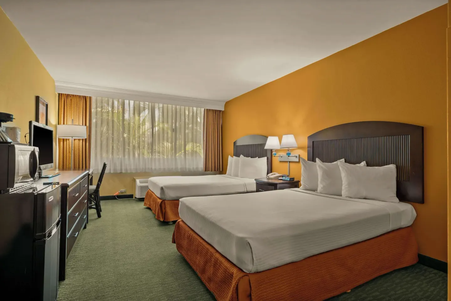 Non-smoking two-bed room with dresser, TV, desk, and window at Airport Honolulu Hotel.