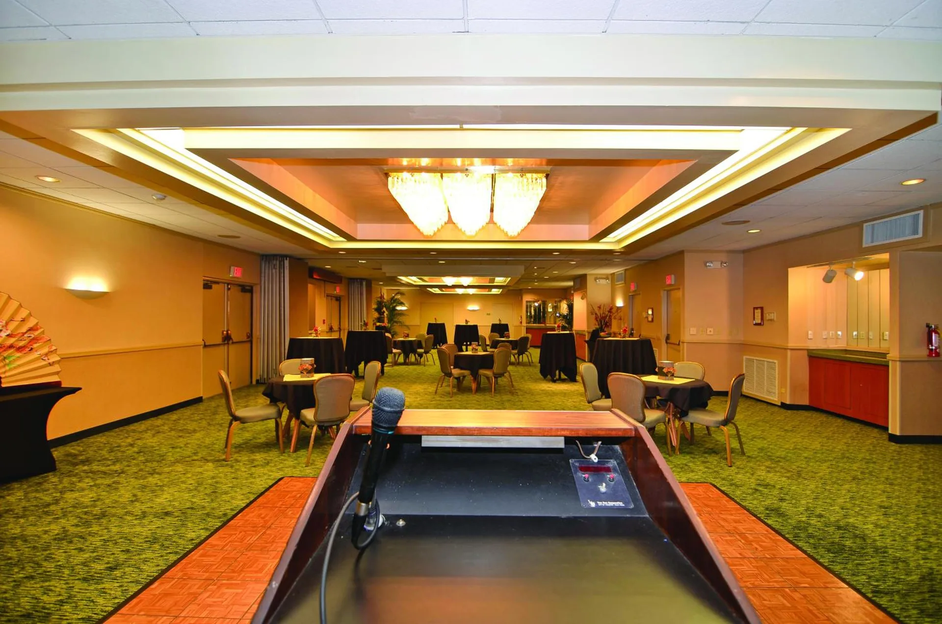 Banquet room with round tables and a lectern at Airport Honolulu Hotel.