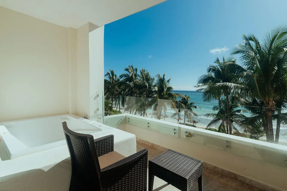 Private balcony with tub, wicker chairs and tropical beach view at Akumal Bay Beach & Wellness Resort