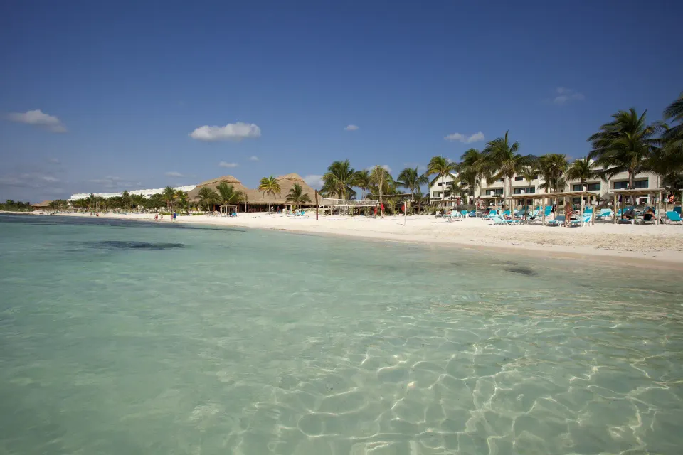 Clear turquoise water, sandy beach and resort buildings at Akumal Bay Beach & Wellness Resort