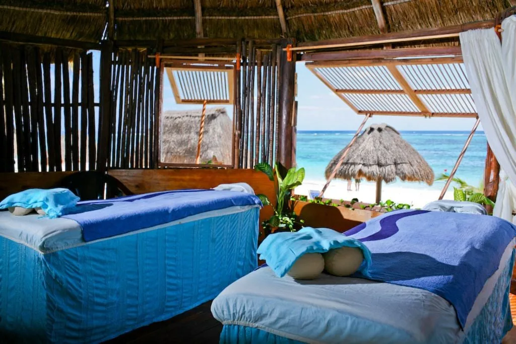 Open-air beachfront massage palapa with two treatment tables at Akumal Bay Beach & Wellness Resort