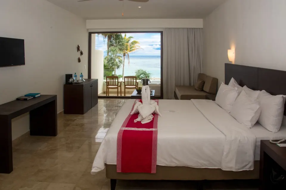 Guest room king bed with terrace and beach view at Akumal Bay Beach & Wellness Resort