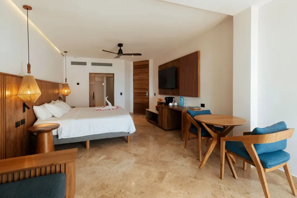 Spacious guest room with king bed and seating area at Akumal Bay Beach & Wellness Resort