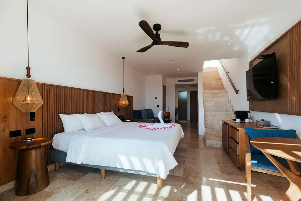 King bed with floral arrangement and ocean-view terrace at Akumal Bay Beach & Wellness Resort