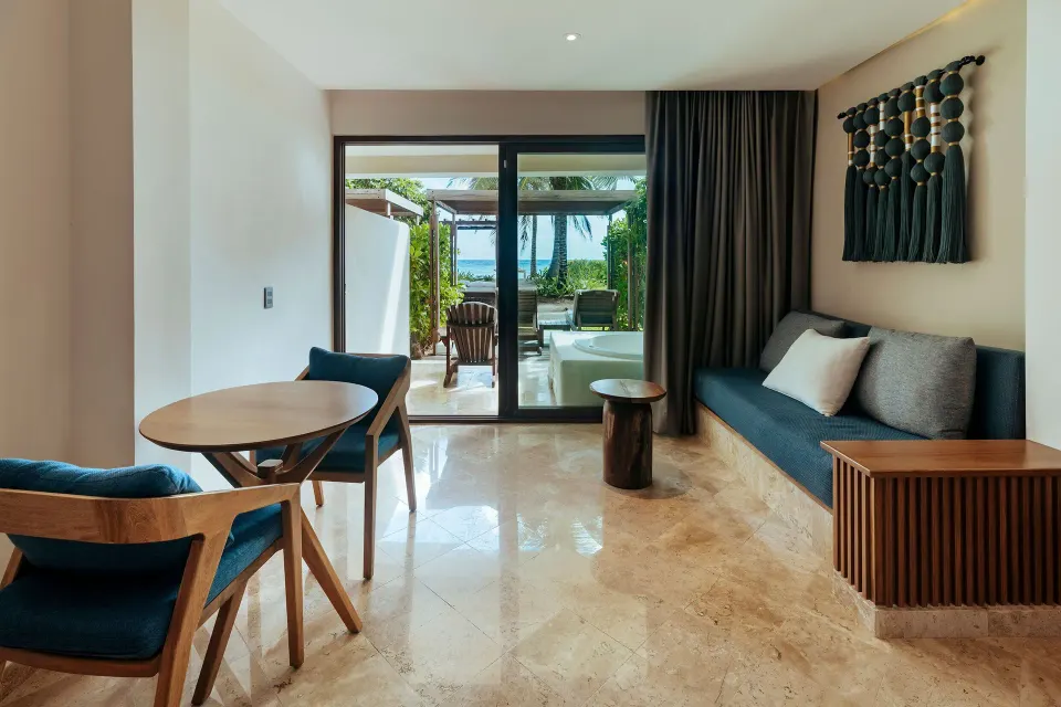 Seating area and sliding doors to terrace with ocean view at Akumal Bay Beach & Wellness Resort