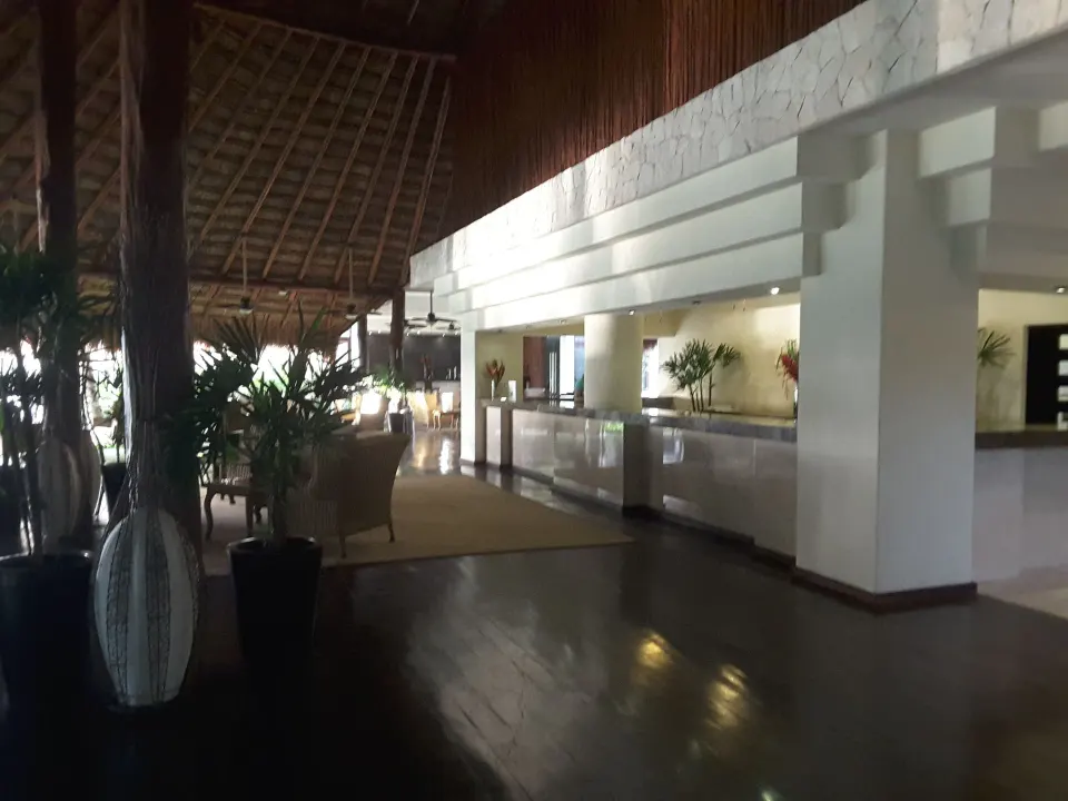 Resort reception desk and lobby seating under thatched ceiling at Akumal Bay Beach & Wellness Resort
