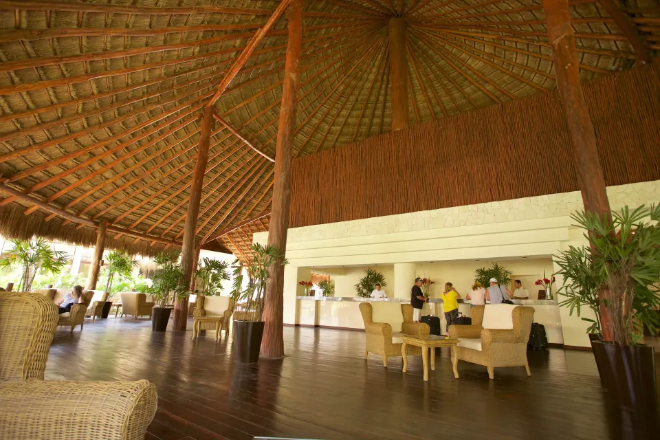 Open-air lobby with high palapa roof and reception desk at Akumal Bay Beach & Wellness Resort