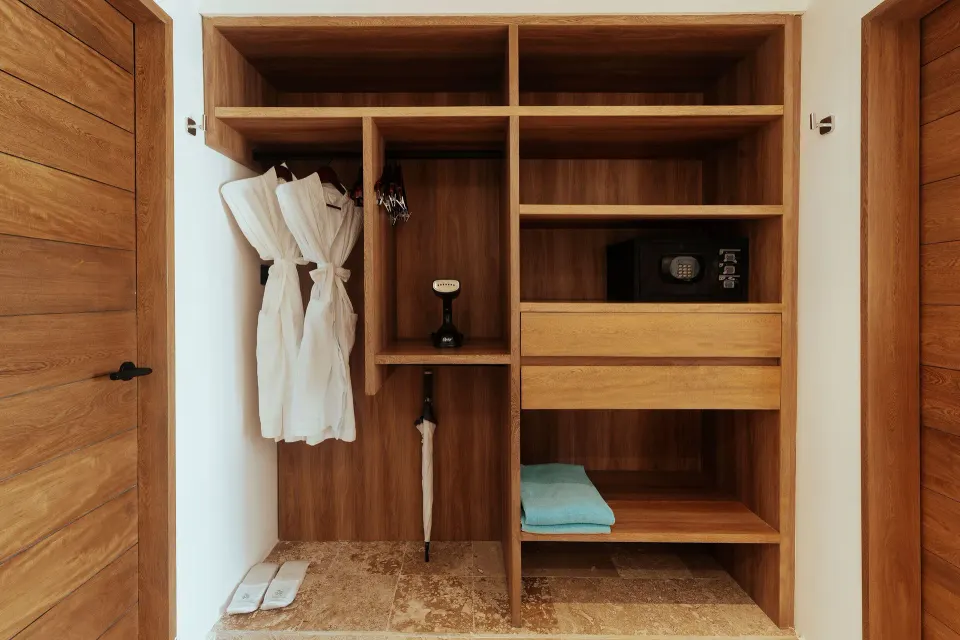 Open wooden closet with robes and safe in a guest room at Akumal Bay Beach & Wellness Resort