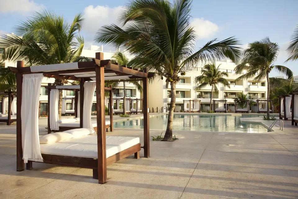 Poolside daybed cabana and resort pool with palm trees at Akumal Bay Beach & Wellness Resort