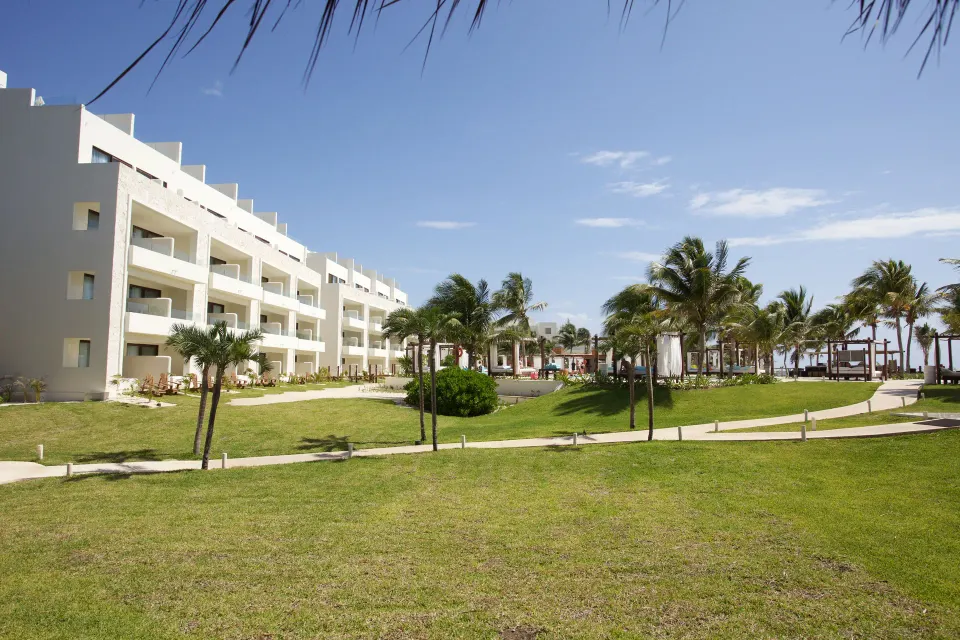 Resort grounds and lawn with multi-story guest building at Akumal Bay Beach & Wellness Resort