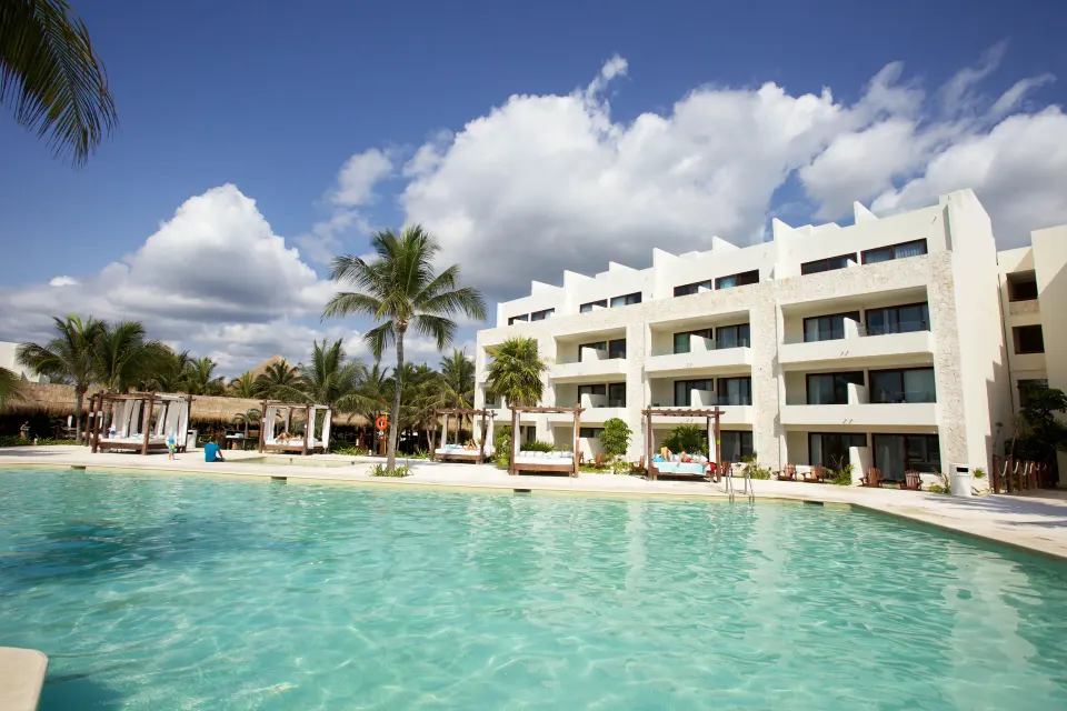 Resort pool with low-rise guest rooms and palms at Akumal Bay Beach & Wellness Resort