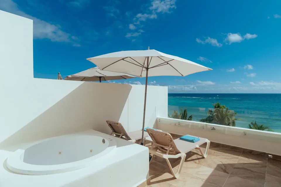 Rooftop terrace with plunge tub, loungers and umbrella overlooking the sea at Akumal Bay Beach & Wellness Resort