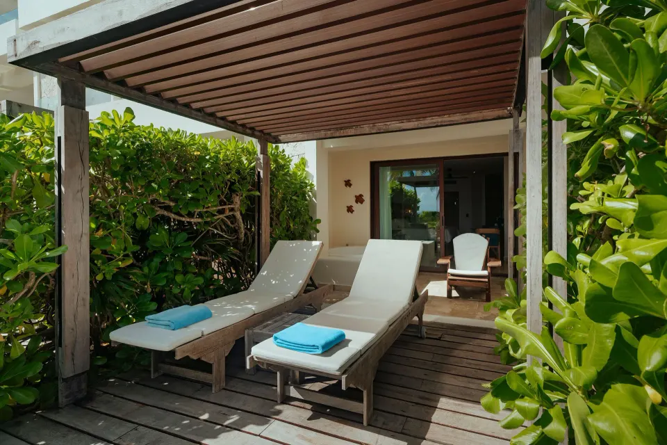 Shaded deck with two loungers and green hedge at Akumal Bay Beach & Wellness Resort