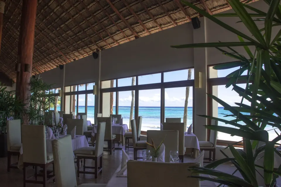 Seaside dining room with tall chairs and ocean view at Akumal Bay Beach & Wellness Resort