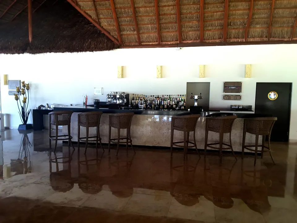 Thatched-roof indoor bar with counter stools at Akumal Bay Beach & Wellness Resort