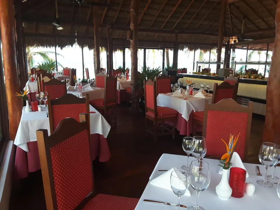 Indoor tropical restaurant dining room with red chairs at Akumal Bay Beach & Wellness Resort
