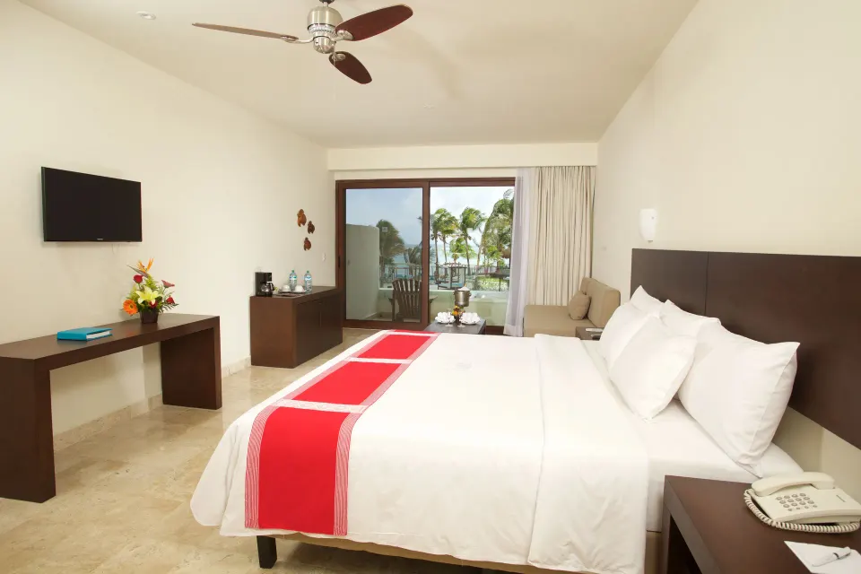 King bed and sliding patio door to garden in a Junior Suite at Akumal Bay Beach & Wellness Resort