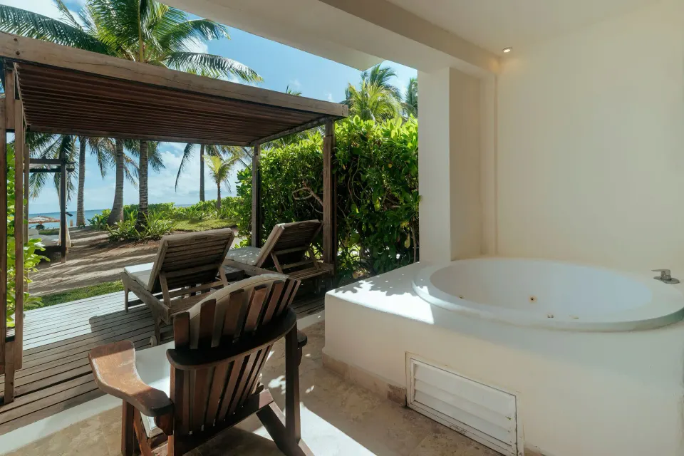 Outdoor terrace with hot tub and loungers facing palms and ocean at Akumal Bay Beach & Wellness Resort