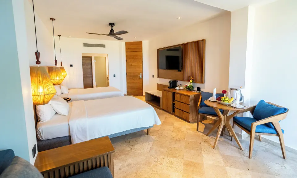 Two beds and a small dining table in a Junior Suite at Akumal Bay Beach & Wellness Resort