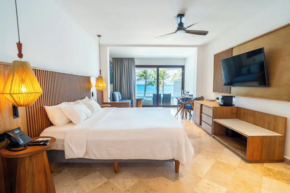 Spacious Junior Suite with king bed, wood accents and balcony at Akumal Bay Beach & Wellness Resort