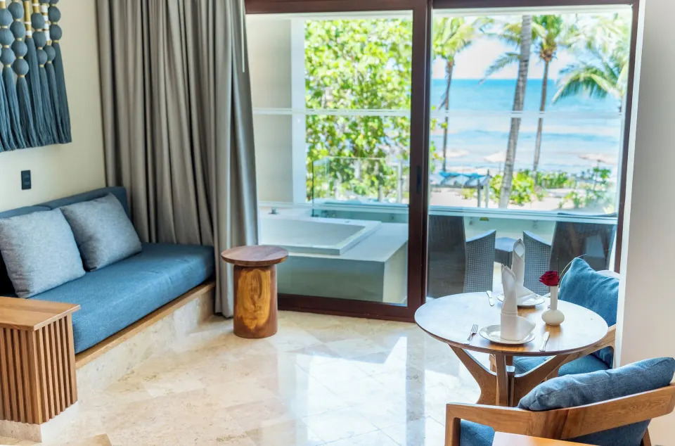 Lounge area with sofa, table and balcony jacuzzi overlooking the sea at Akumal Bay Beach & Wellness Resort