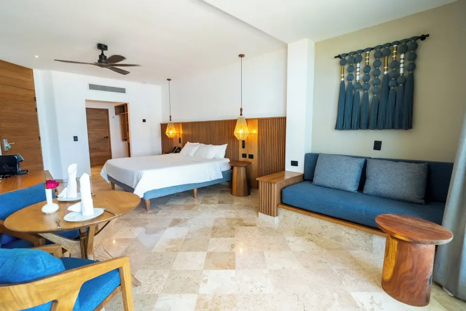 Junior Suite open plan with king bed, dining table and sofa at Akumal Bay Beach & Wellness Resort