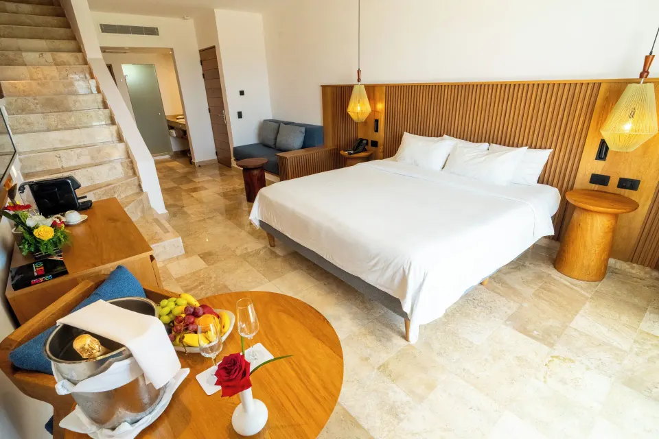 Junior Suite Penthouse king bed and stairway to rooftop terrace at Akumal Bay Beach & Wellness Resort