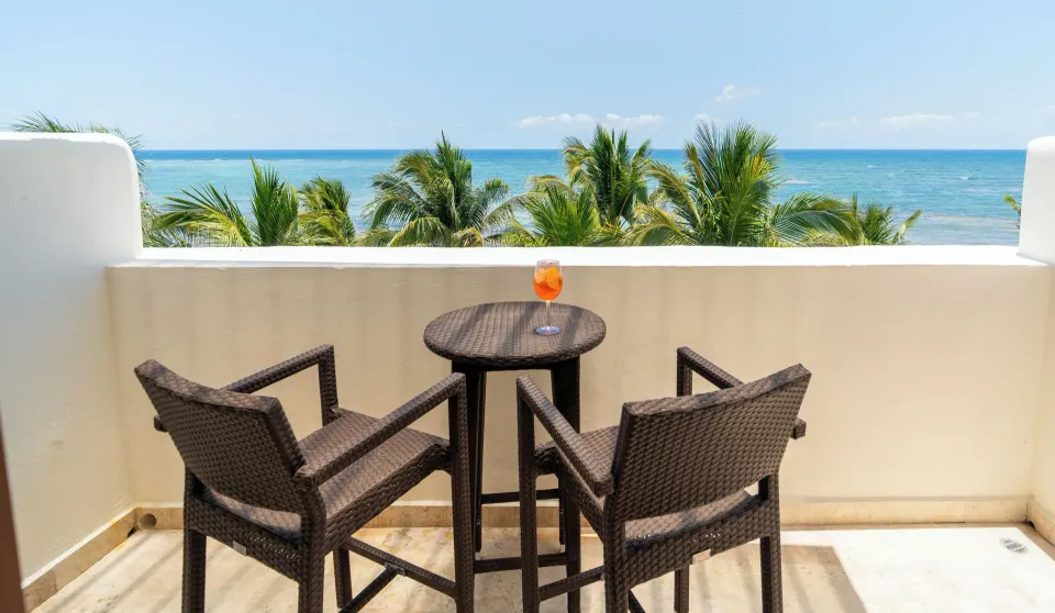 Terrace bistro table and two chairs with palm trees and ocean at Akumal Bay Beach & Wellness Resort