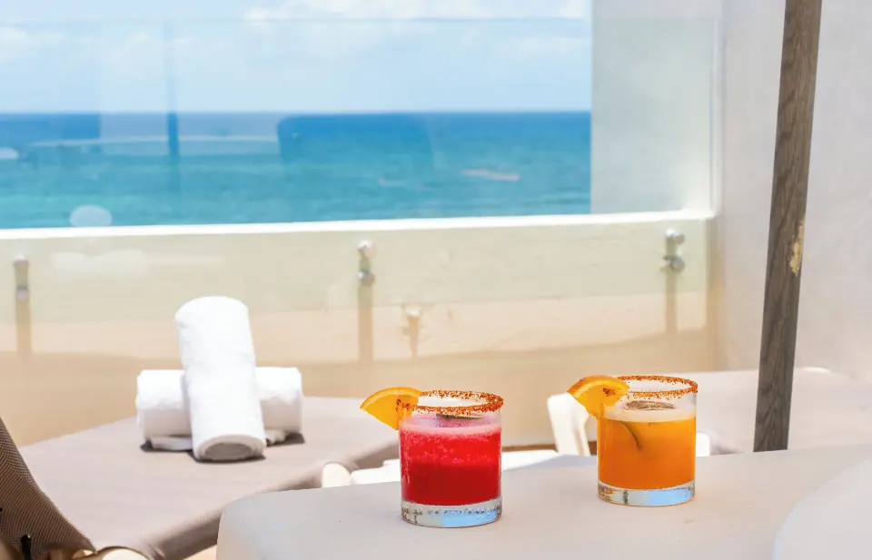 Cocktails on terrace table with ocean beyond at Akumal Bay Beach & Wellness Resort