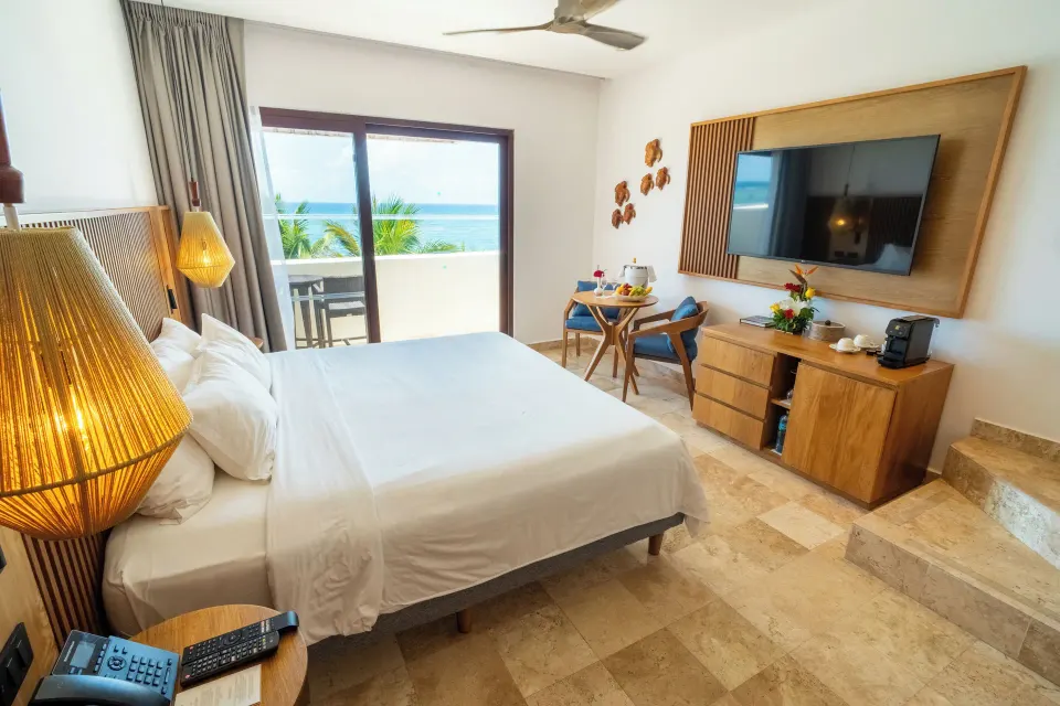 Junior Suite Penthouse king bed with balcony table and ocean view at Akumal Bay Beach & Wellness Resort