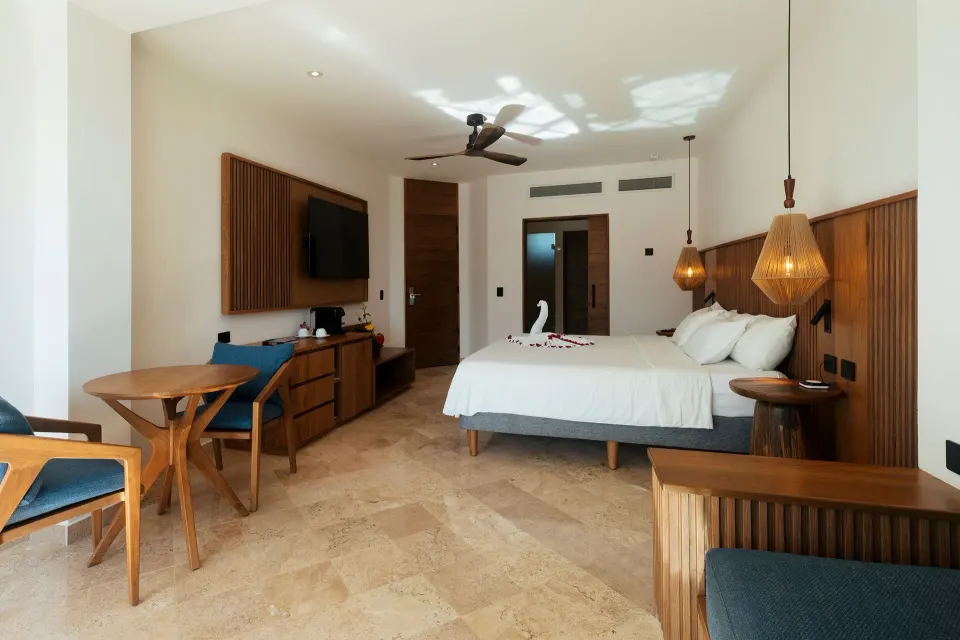 Interior view of Junior Suite Premium Ocean Front showing bed, seating and entry at Akumal Bay Beach & Wellness Resort