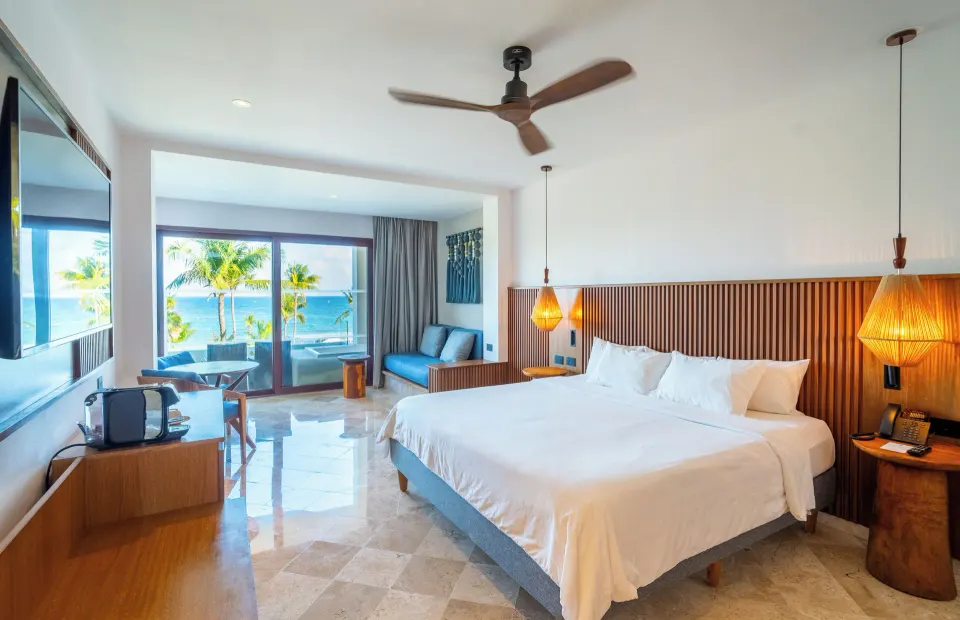 Wide view of Junior Suite with king bed and ocean visible from balcony at Akumal Bay Beach & Wellness Resort