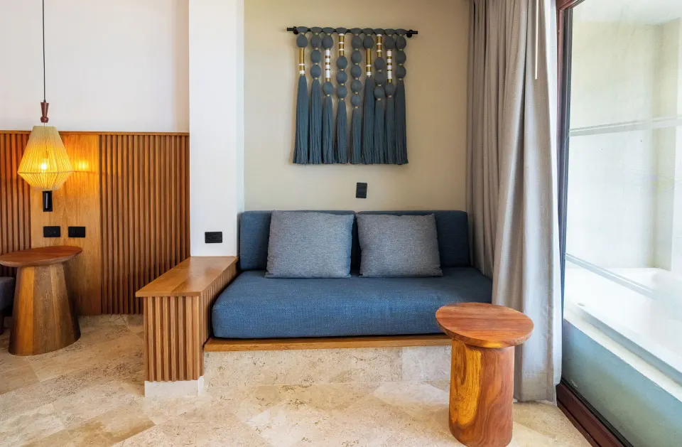 Seating nook with sofa and wood side table in a Junior Suite at Akumal Bay Beach & Wellness Resort