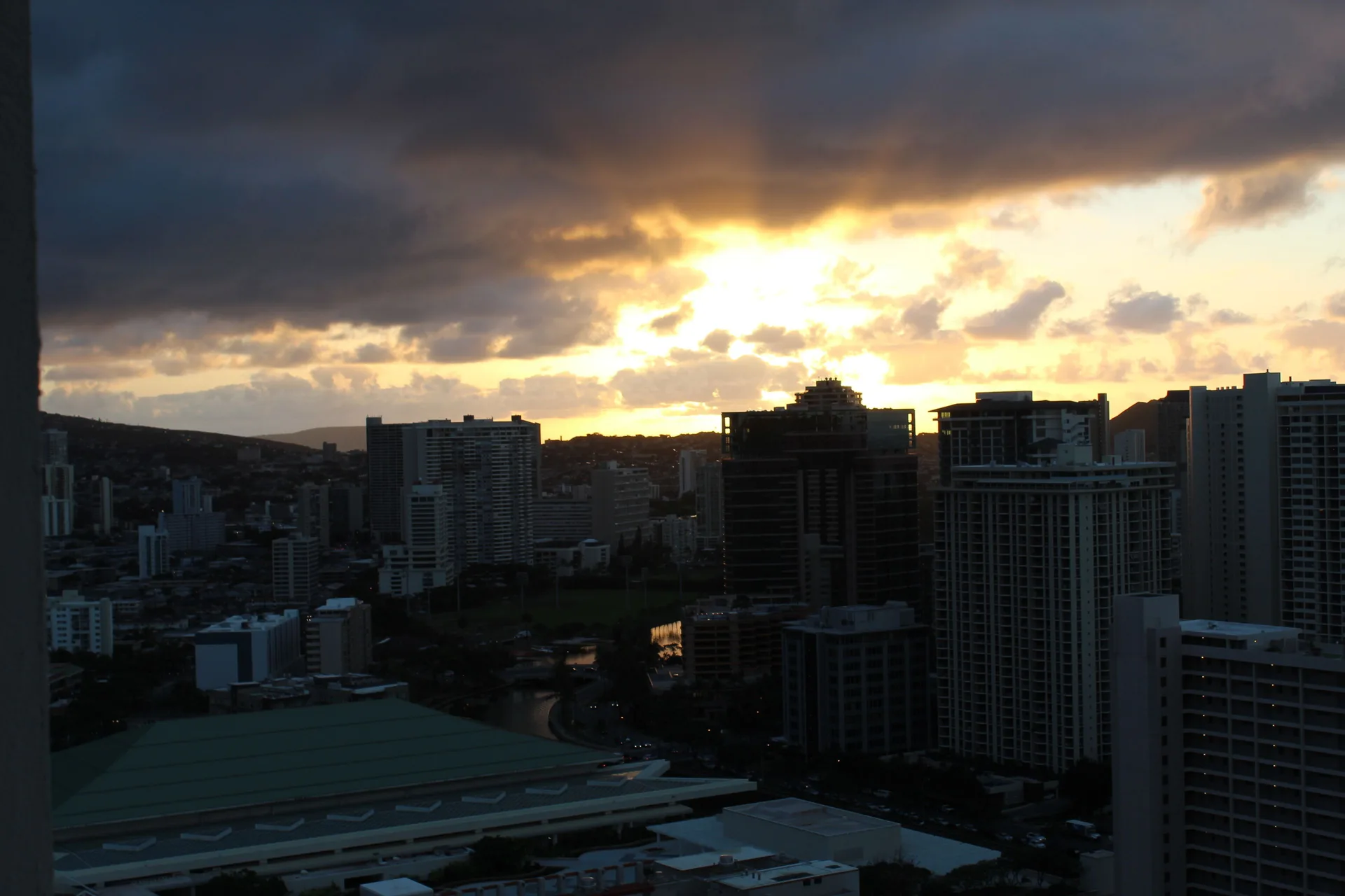 Dramatic sunset over the city skyline from Ala Moana Hotel with dark clouds.