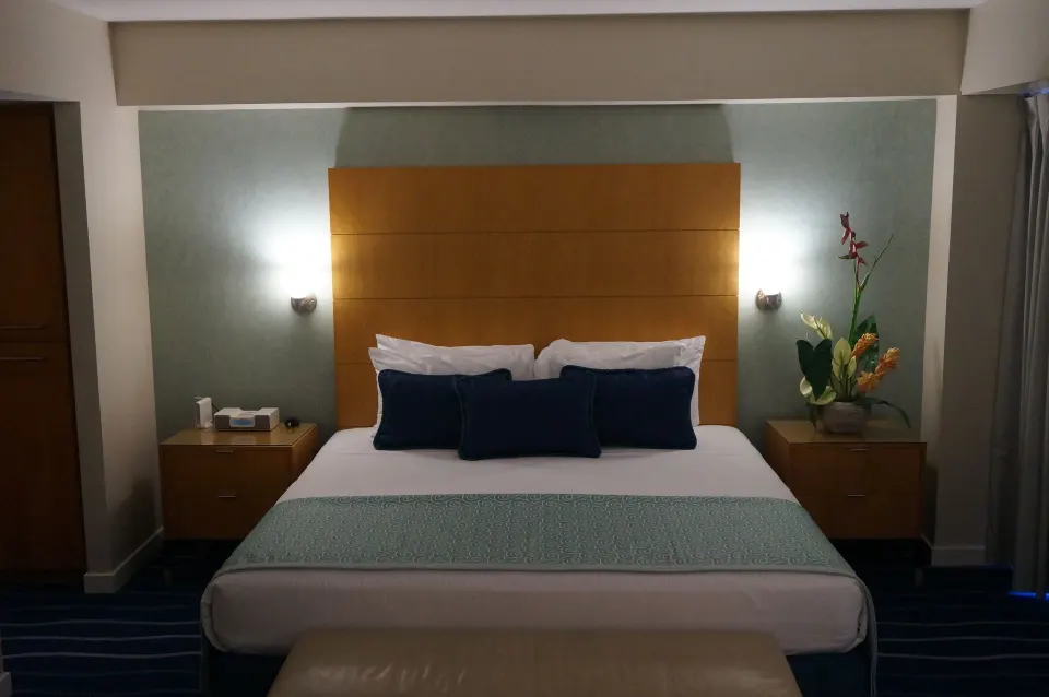 King bed with wood headboard and bedside tables in a guest room at Ala Moana Hotel.