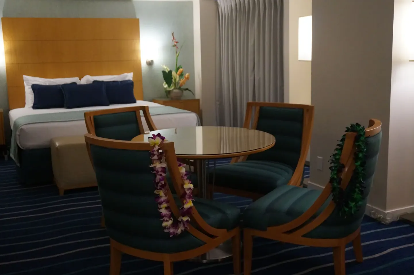 Guest room with king bed, round dining table, and four chairs at Ala Moana Hotel.