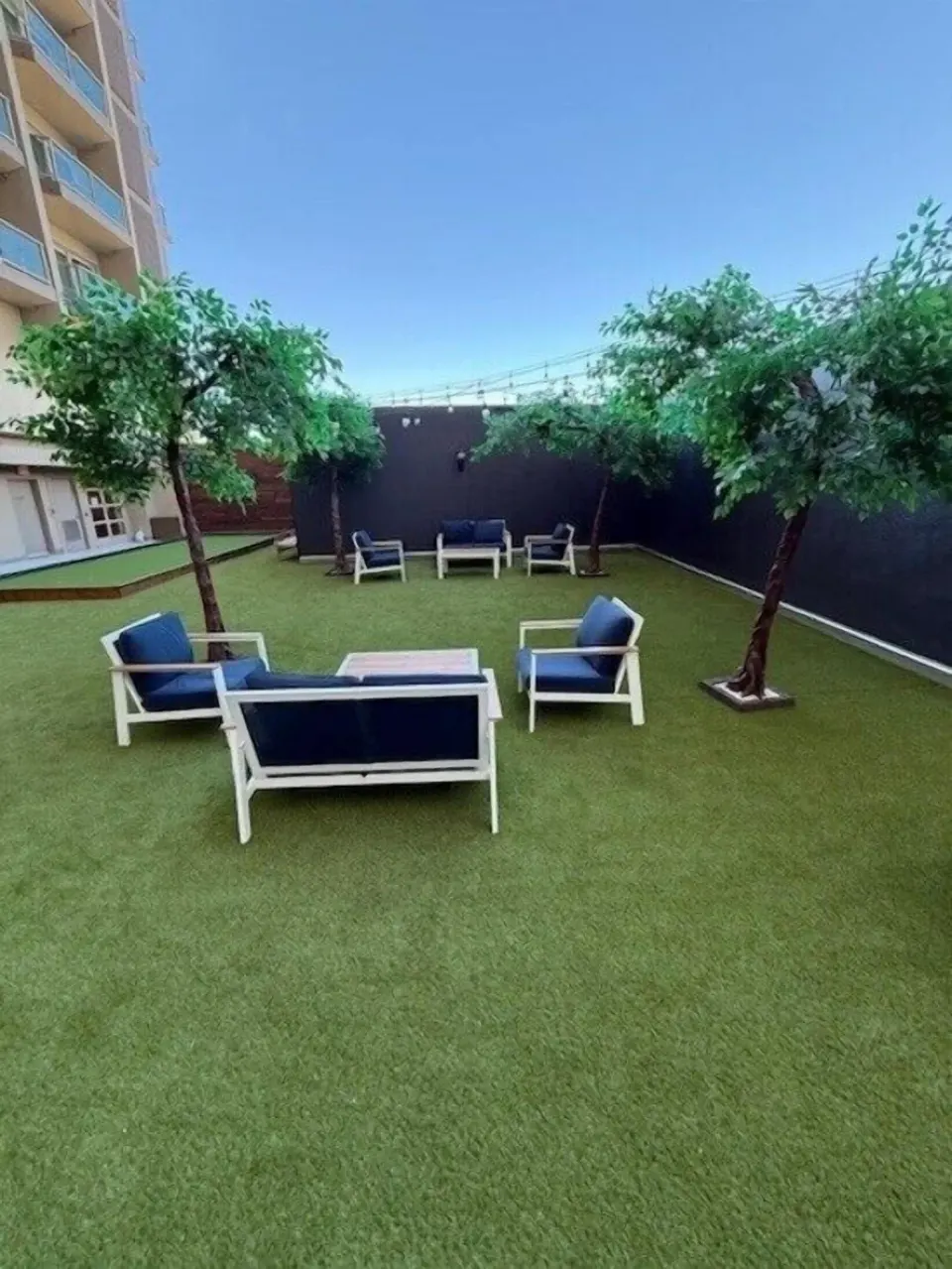 Outdoor lounge area with turf, sofas and small trees at Ala Moana Hotel.