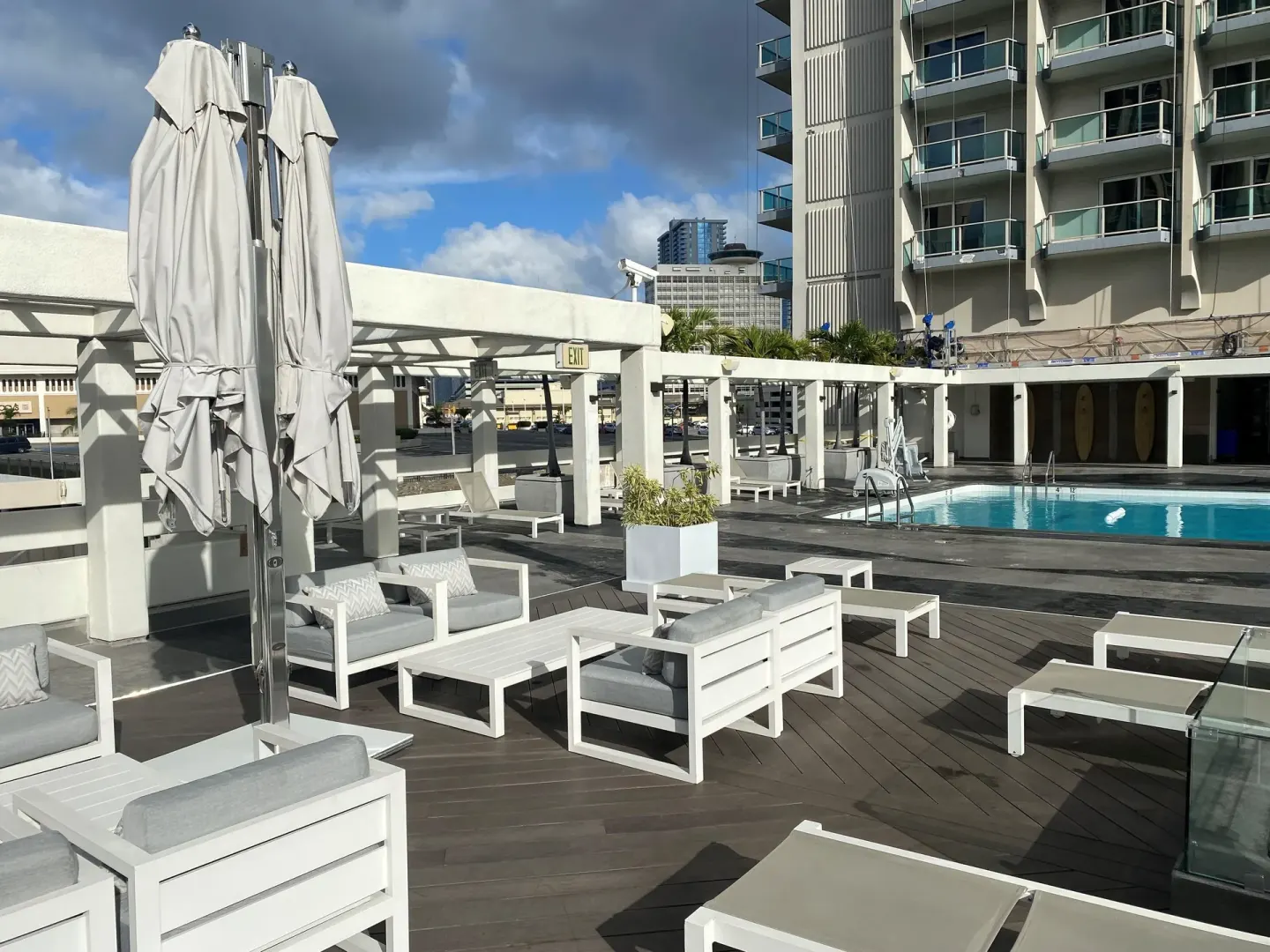 Outdoor pool lounge seating with umbrellas and city views at Ala Moana Hotel.