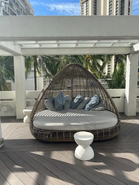 Wicker daybed with pillows on an outdoor terrace at Ala Moana Hotel.