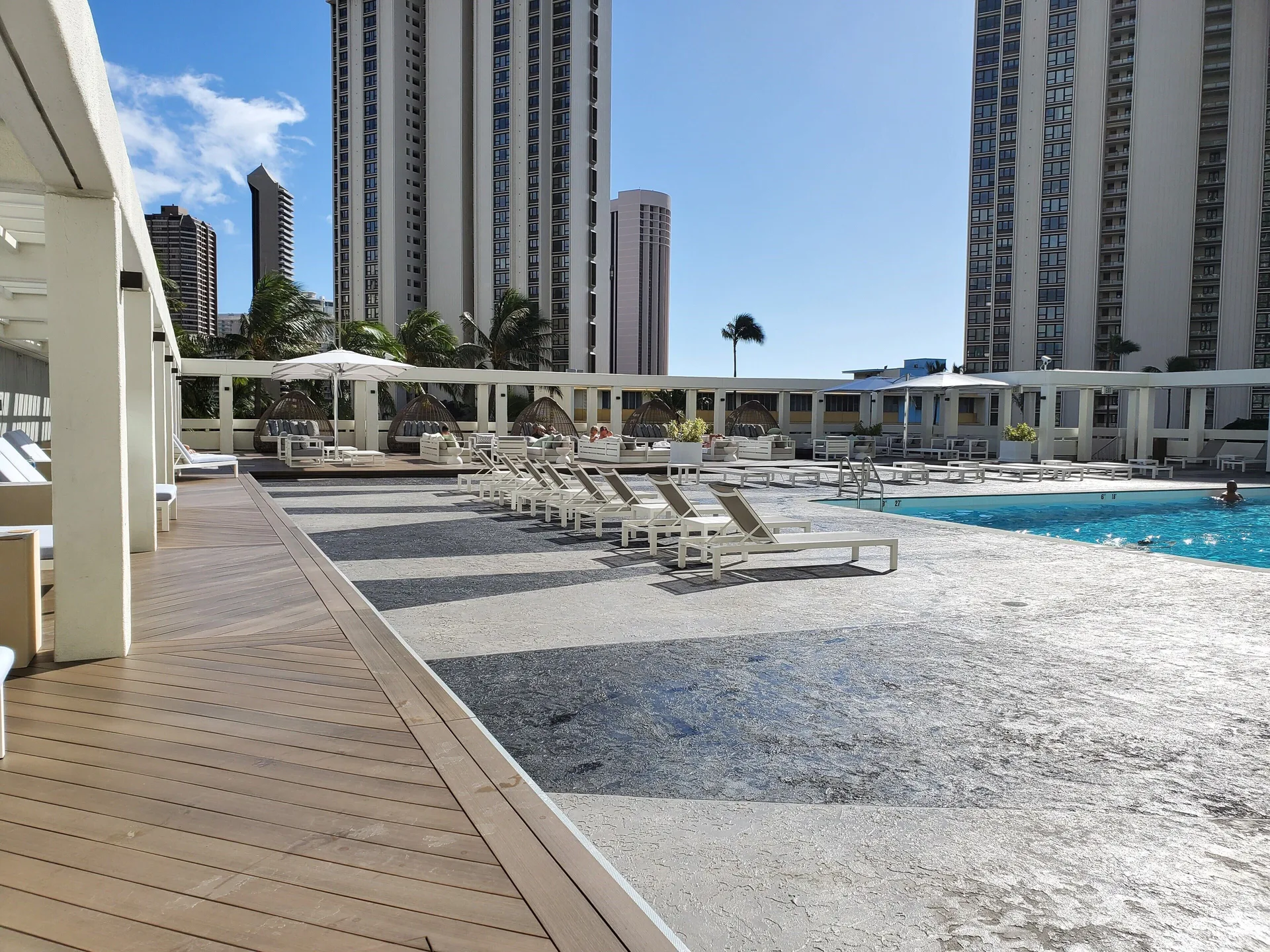 Pool deck with lounge chairs and city towers at Ala Moana Hotel.
