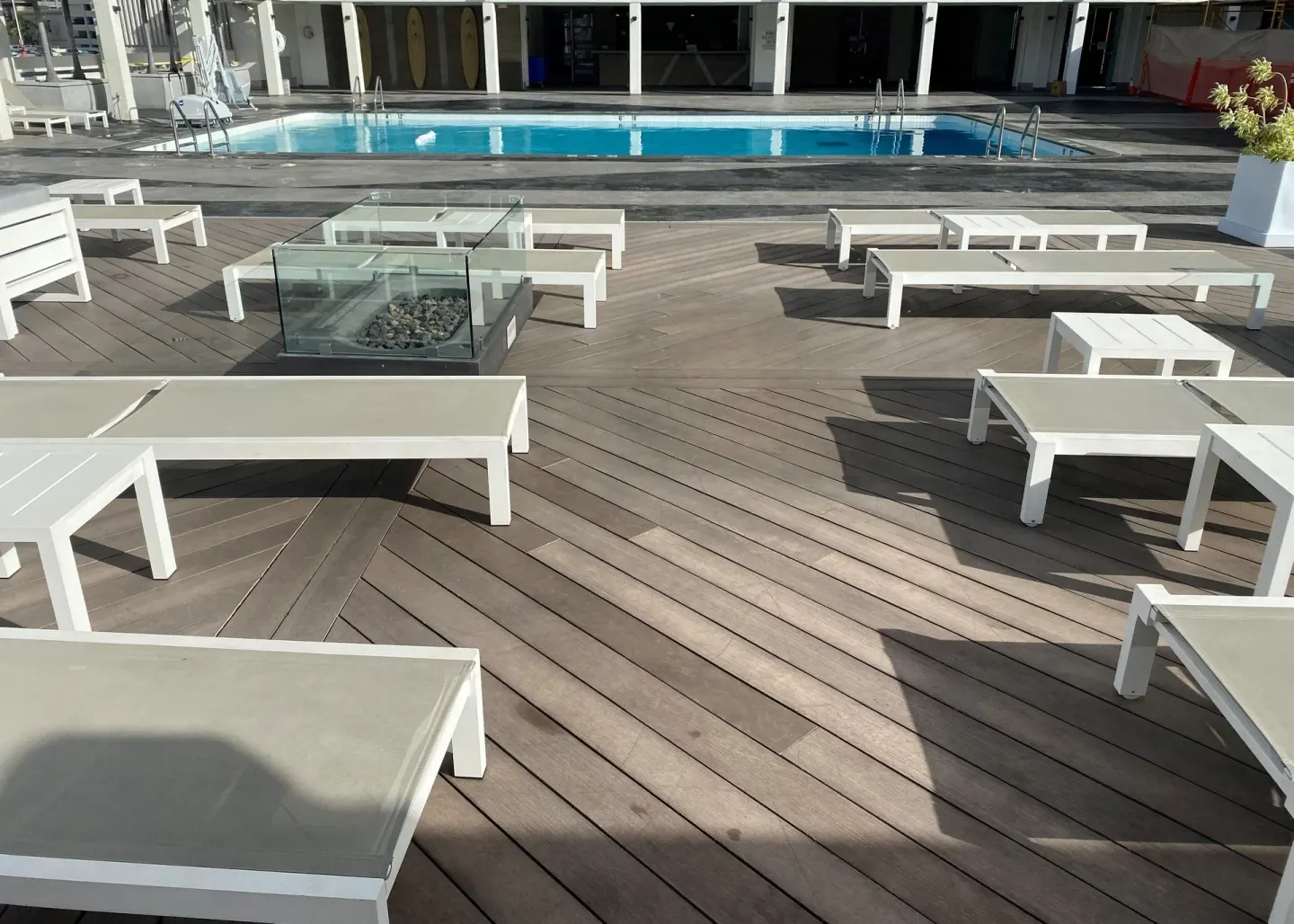 Pool deck with white loungers and a glass fire feature at Ala Moana Hotel.