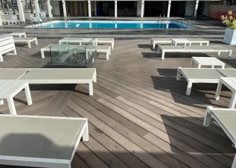 Pool deck with white loungers and a glass fire feature at Ala Moana Hotel.