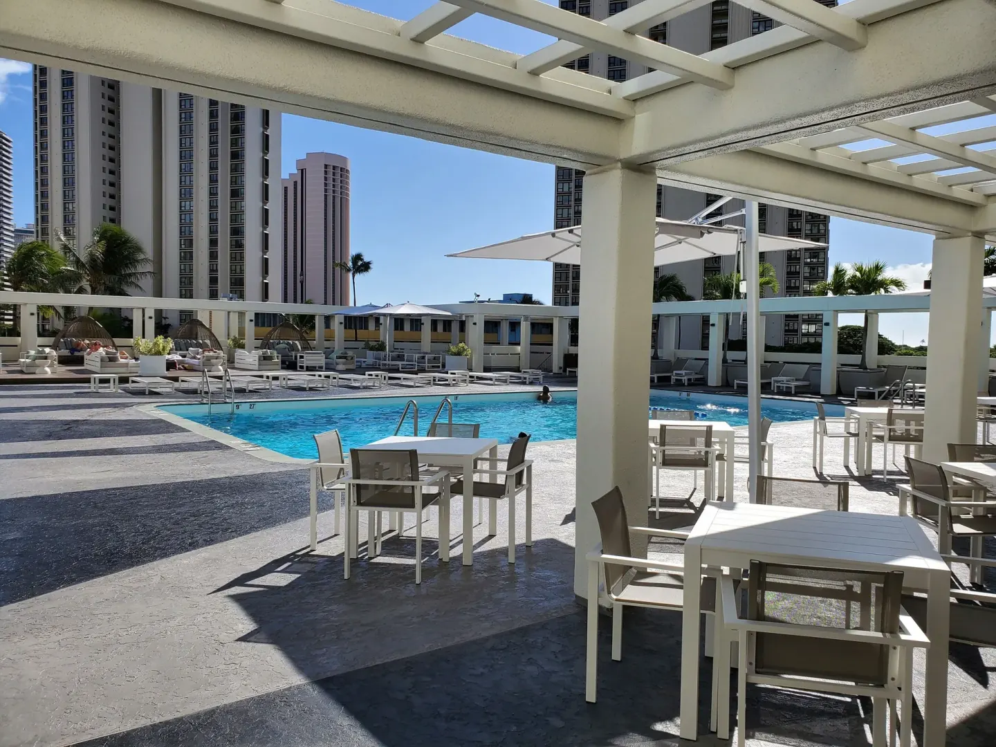 Pool deck with tables, umbrellas, and lounge chairs at Ala Moana Hotel.