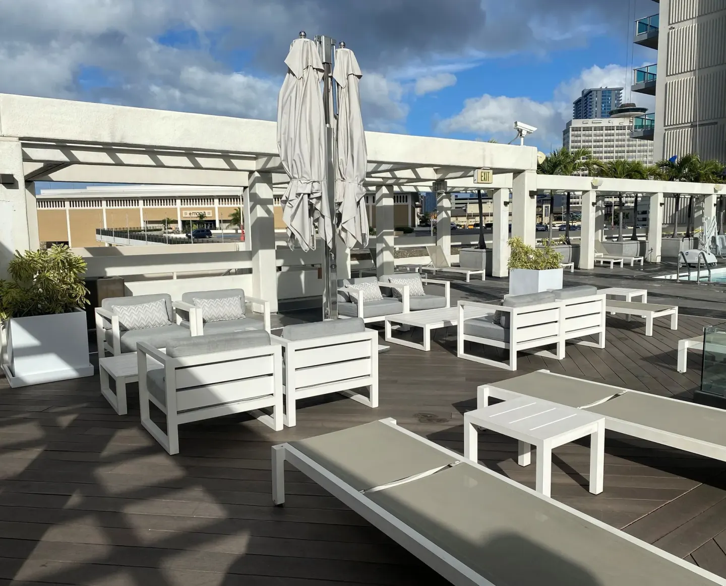 Pool deck seating with sofas, loungers, and closed umbrellas at Ala Moana Hotel.