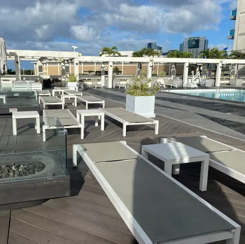 Poolside loungers, planters, and city skyline at Ala Moana Hotel.