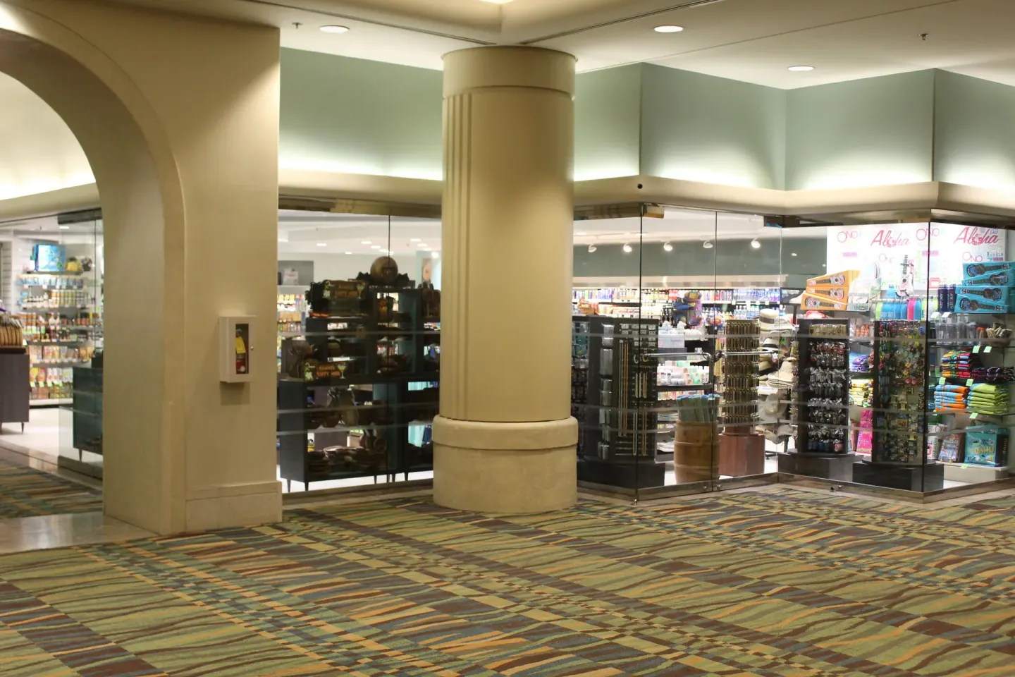 Ala Moana Hotel corridor with glass storefronts and souvenir displays around a central column.