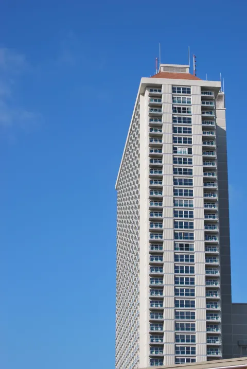 Upper floors of Ala Moana Hotel tower against a clear blue sky.
