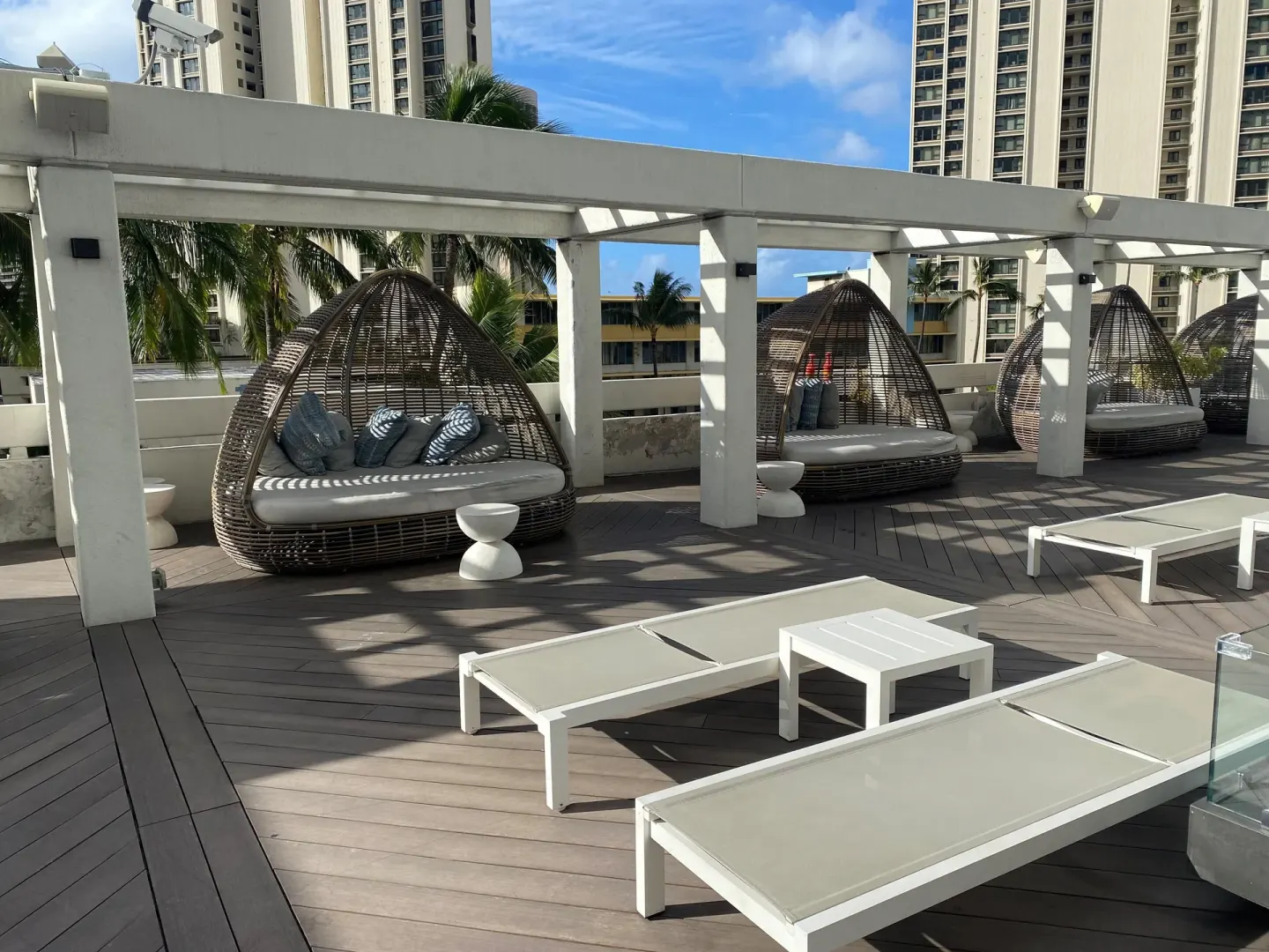 Wicker daybeds and white loungers on the pool deck at Ala Moana Hotel.