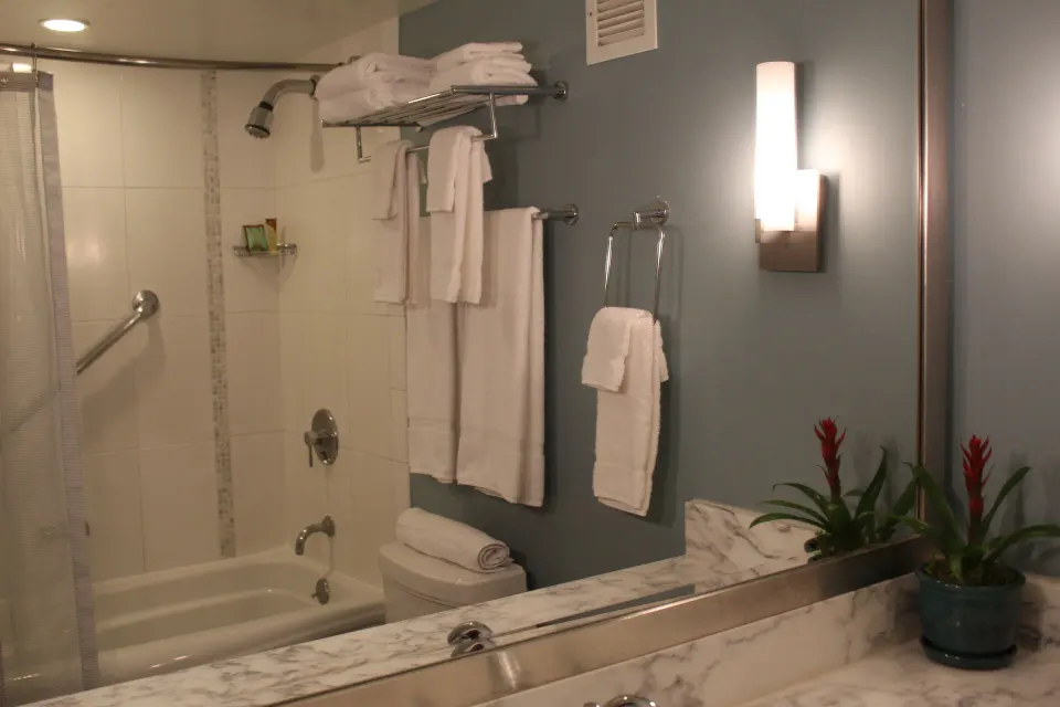 Standard Room bathroom with tub shower, towels, and vanity mirror at Ala Moana Hotel.