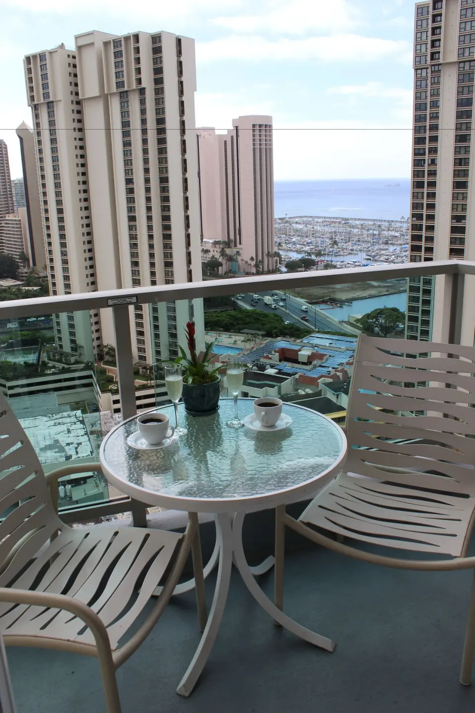Balcony table and two chairs overlooking the marina and ocean from Ala Moana Hotel.